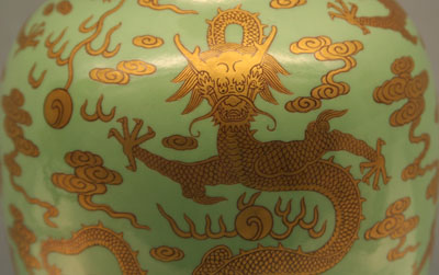 Vase with a golden dragon and cloud design on a green background